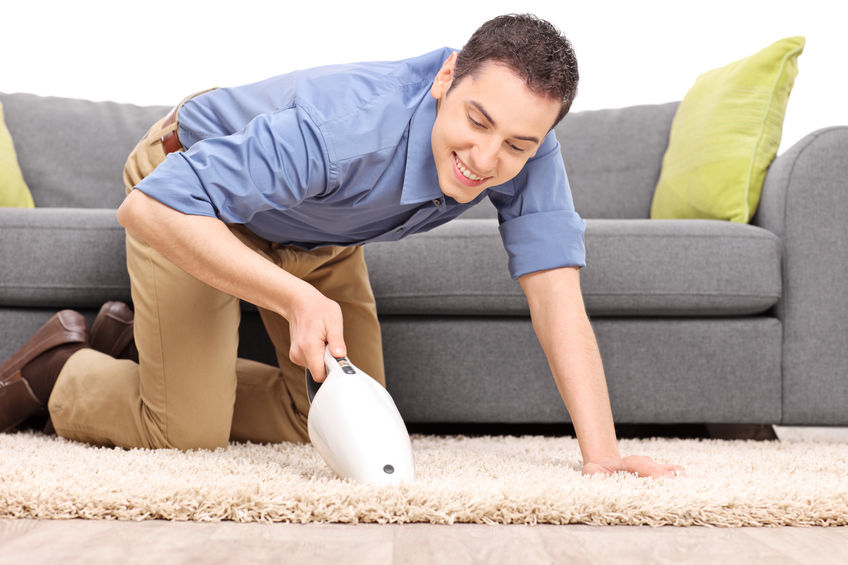 39282202 - young joyful man vacuuming a carpet with a handheld vacuum cleaner isolated on white background