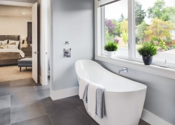 47256462 - bathtub in master bathroom in new luxury home with view of master bedroom and neighborhood with trees  through window