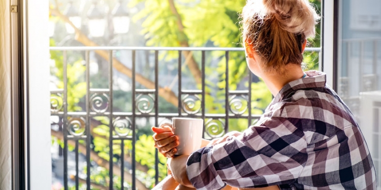 52650465 - young pretty woman  sitting at opened window drinking coffee and looking outside enjoys of rest