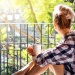 52650465 - young pretty woman  sitting at opened window drinking coffee and looking outside enjoys of rest